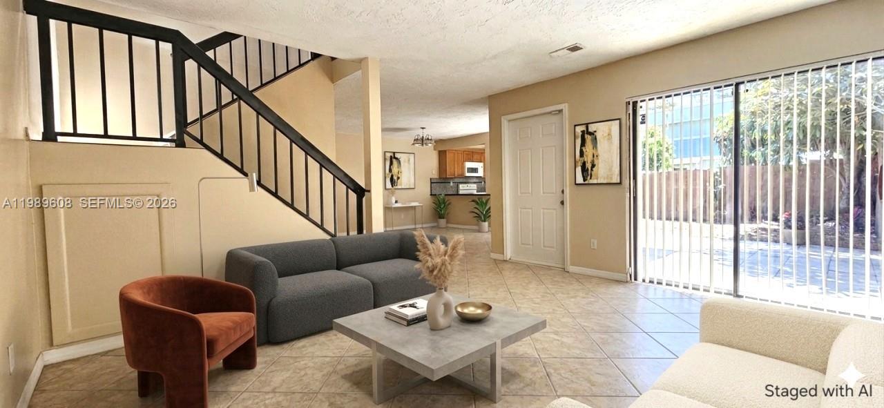This living room features tile flooring, a staircase with black railings, and sliding glass doors — 610 Commodore Dr, Plantation FL 33325, PLANTATION, FL