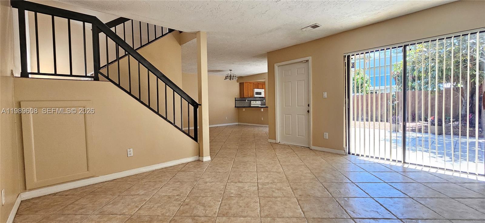 A room with tile flooring features a staircase with black railings and a sliding door — 610 Commodore Dr, Plantation FL 33325, PLANTATION, FL