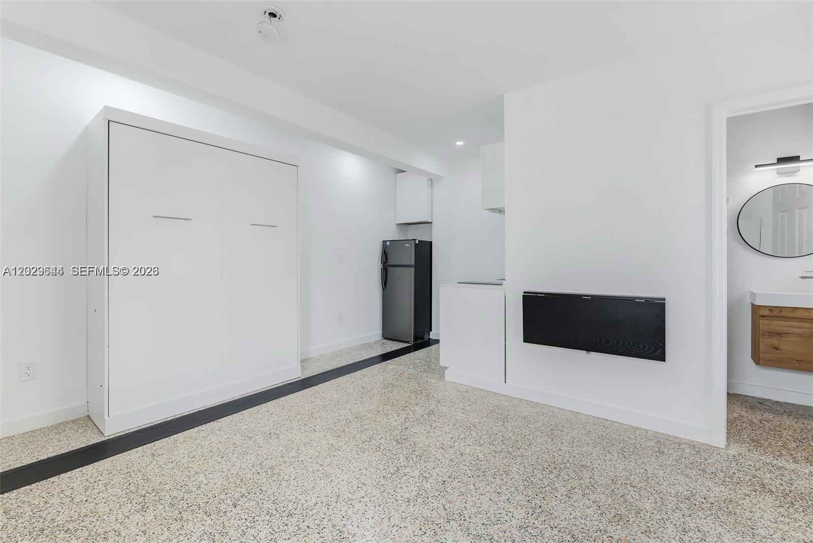 A studio apartment features a white Murphy bed, a kitchenette, and a wall-mounted folding table — 415 75th St # 4A, Miami Beach FL 33141, MIAMI BEACH, FL