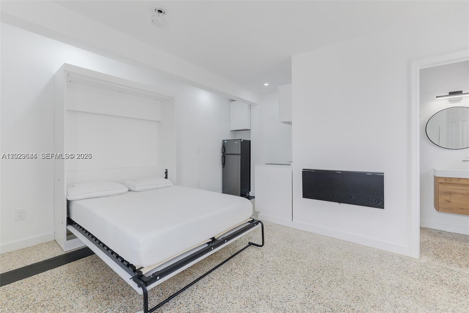 A studio apartment features a white Murphy bed, a small kitchenette, and a bathroom entrance — 415 75th St # 4A, Miami Beach FL 33141, MIAMI BEACH, FL