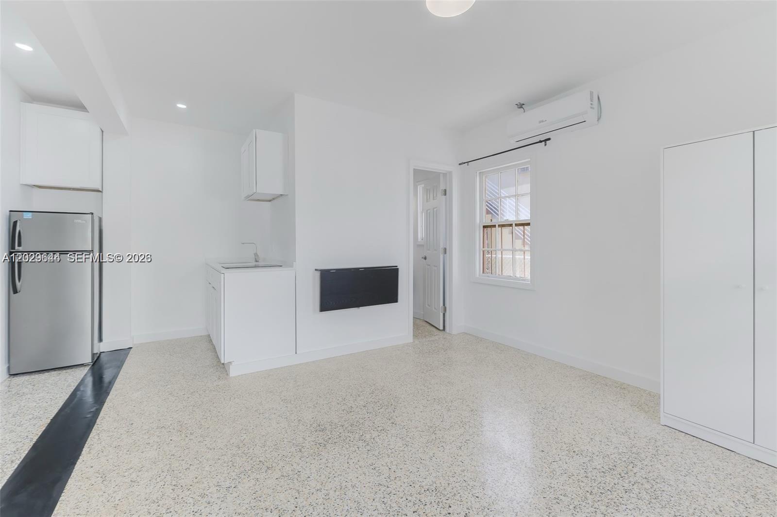 A small kitchen area features white cabinets, a stainless refrigerator, and a wall-mounted table — 415 75th St # 4A, Miami Beach FL 33141, MIAMI BEACH, FL