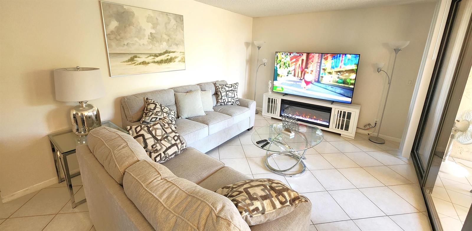 A living room features a gray sofa, a glass coffee table, and a television console — 750 Egret Circle # 6404, Delray Beach FL 33444, DELRAY BEACH, FL