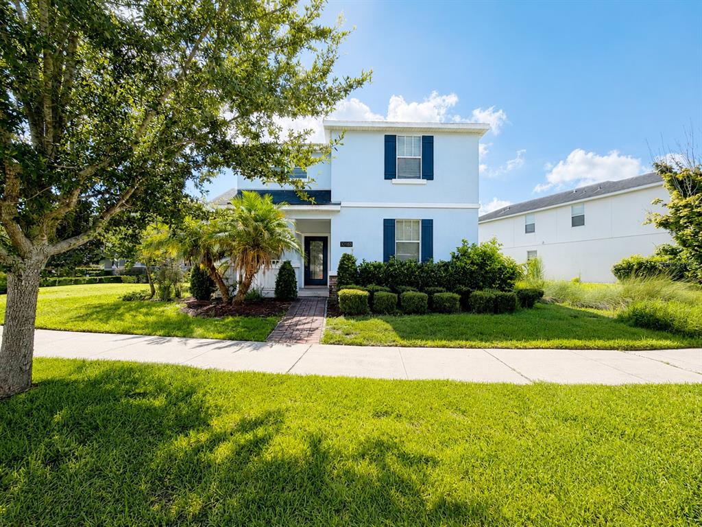 A two-story light blue house with dark shutters and a brick walkway stands behind a lawn — 10188 AUTHORS WAY, ORLANDO, FL