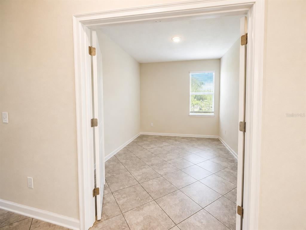 A room with tile flooring and a window is viewed through an open doorway — 10188 AUTHORS WAY, ORLANDO, FL