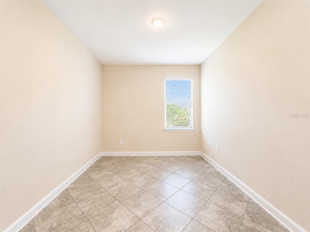 An empty room with beige walls, tile flooring, a single window, and a ceiling light — 10188 AUTHORS WAY, ORLANDO, FL