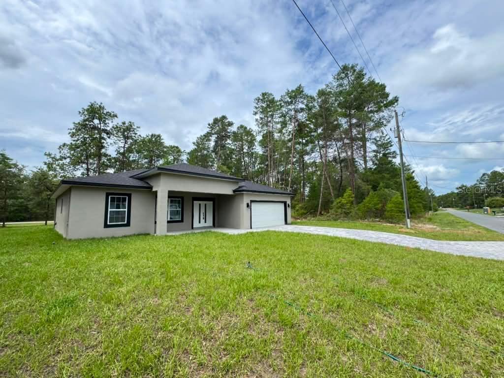 A modern, single-story house with a gray exterior, a white garage door, and a grassy yard — 1458 W LANDMARK DRIVE, CITRUS SPRINGS, FL