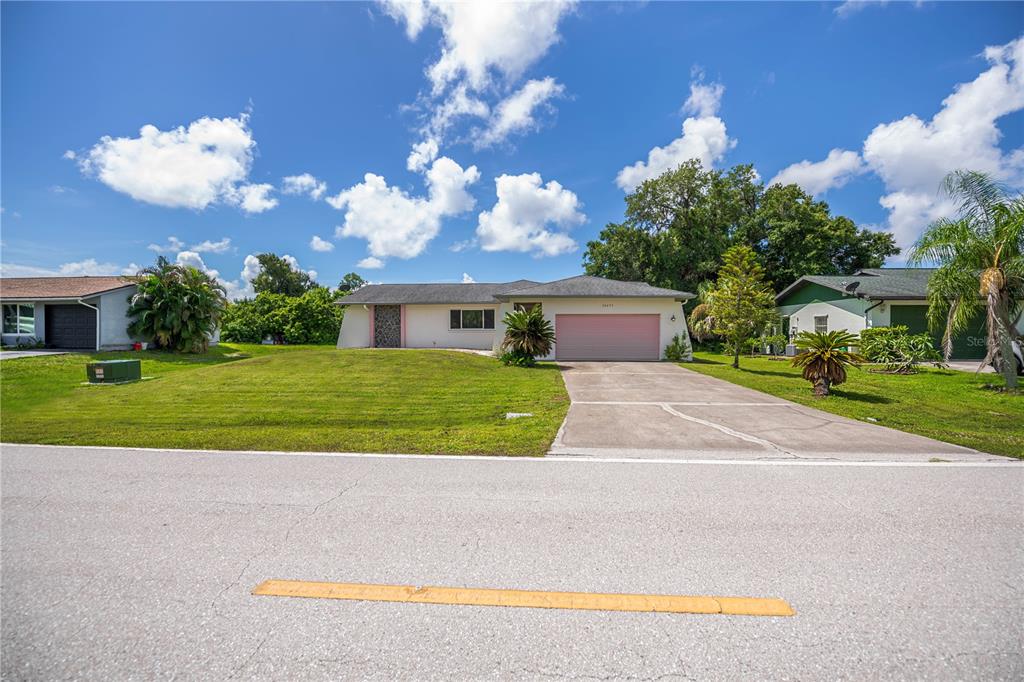 A single-story house with a pink garage door and a concrete driveway under a blue sky — 20255 LORENZO AVENUE, PORT CHARLOTTE, FL