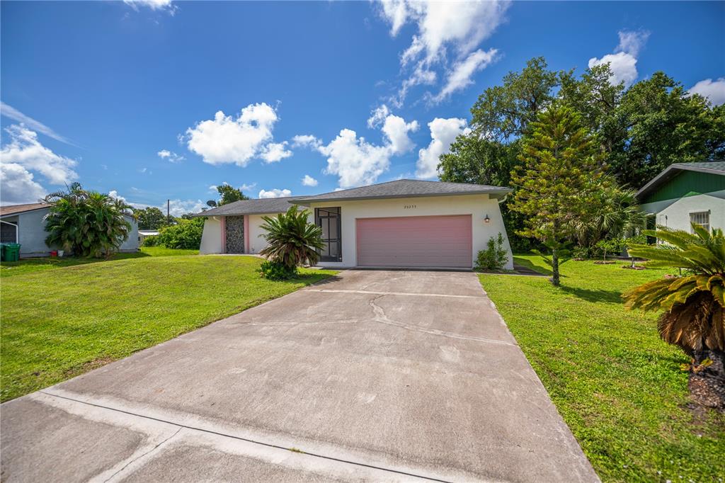 A single-story house with a pink garage door and a concrete driveway under a blue sky — 20255 LORENZO AVENUE, PORT CHARLOTTE, FL