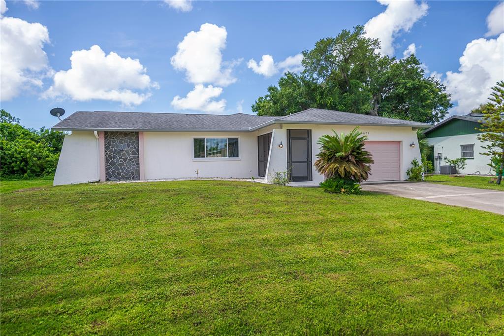A single-story house with a white exterior, stone accent wall, and an attached garage — 20255 LORENZO AVENUE, PORT CHARLOTTE, FL