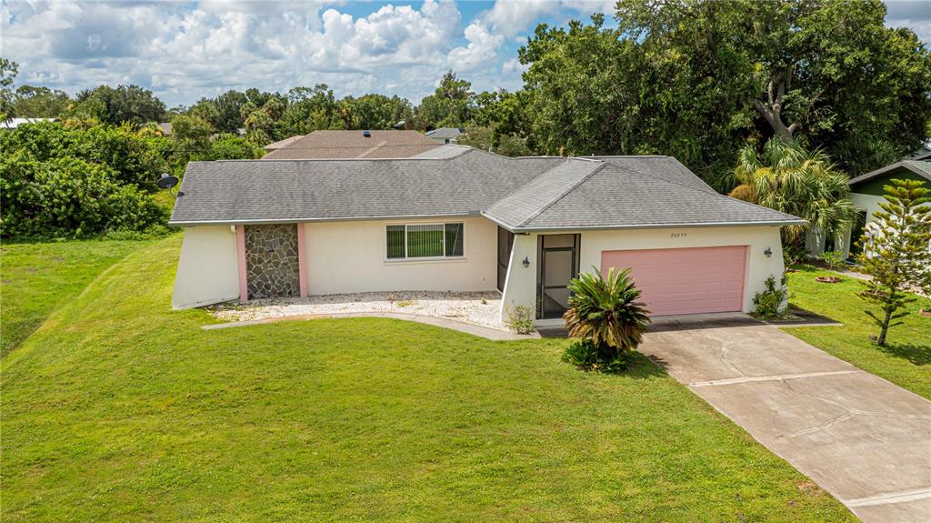 A single-story house with a pink garage door, stone accent wall, and a concrete driveway — 20255 LORENZO AVENUE, PORT CHARLOTTE, FL
