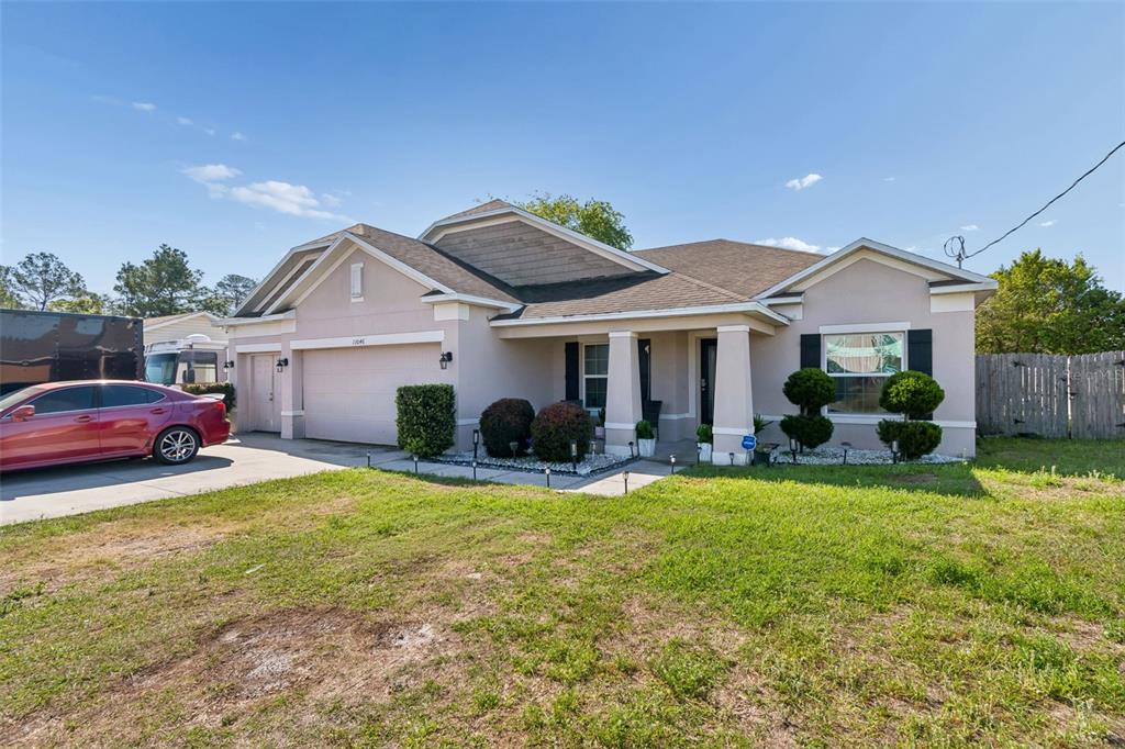 A single-story house with a beige stucco exterior, a two-car garage, and a front porch — 13046 LINDEN DRIVE, SPRING HILL, FL