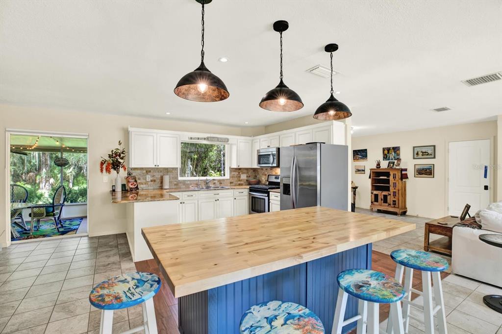 A kitchen features a blue island with a wood countertop, white cabinets, and pendant lighting — 4064 N CONCORD DRIVE, CRYSTAL RIVER, FL