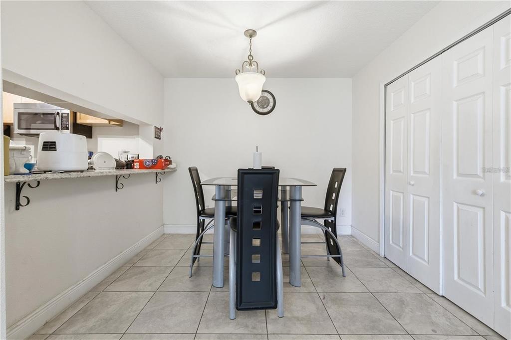 A dining area with a glass-top table, black chairs, tile flooring, and a breakfast bar — 5219 VIA HACIENDA CIRCLE UNIT B111, ORLANDO, FL