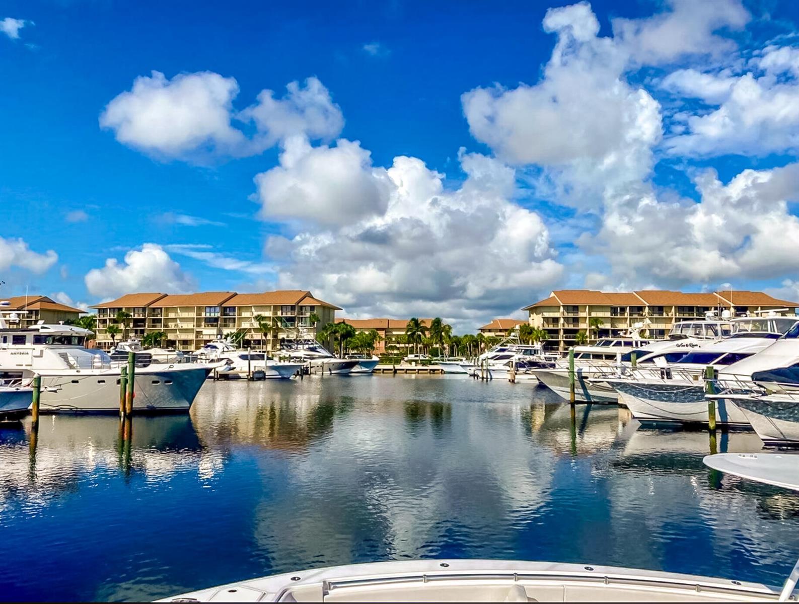 A view from a boat looking toward a marina with docked yachts and apartment buildings — 1701 Marina Isle Way # 103, Jupiter FL 33477, JUPITER, FL