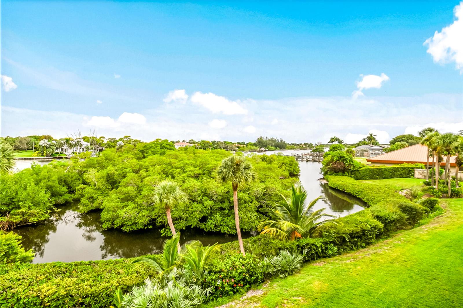 An elevated view of a lush green landscape with a winding waterway and palm trees — 1701 Marina Isle Way # 103, Jupiter FL 33477, JUPITER, FL
