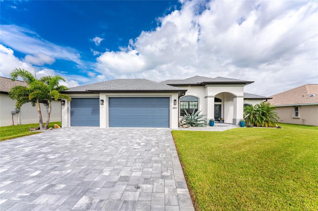 A single-story house with a blue three-car garage and a paved driveway under a sky — 940 BOUNDARY BOULEVARD, ROTONDA WEST, FL