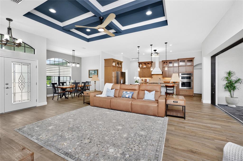 An open-concept living room and kitchen feature a blue coffered ceiling and wood flooring — 940 BOUNDARY BOULEVARD, ROTONDA WEST, FL