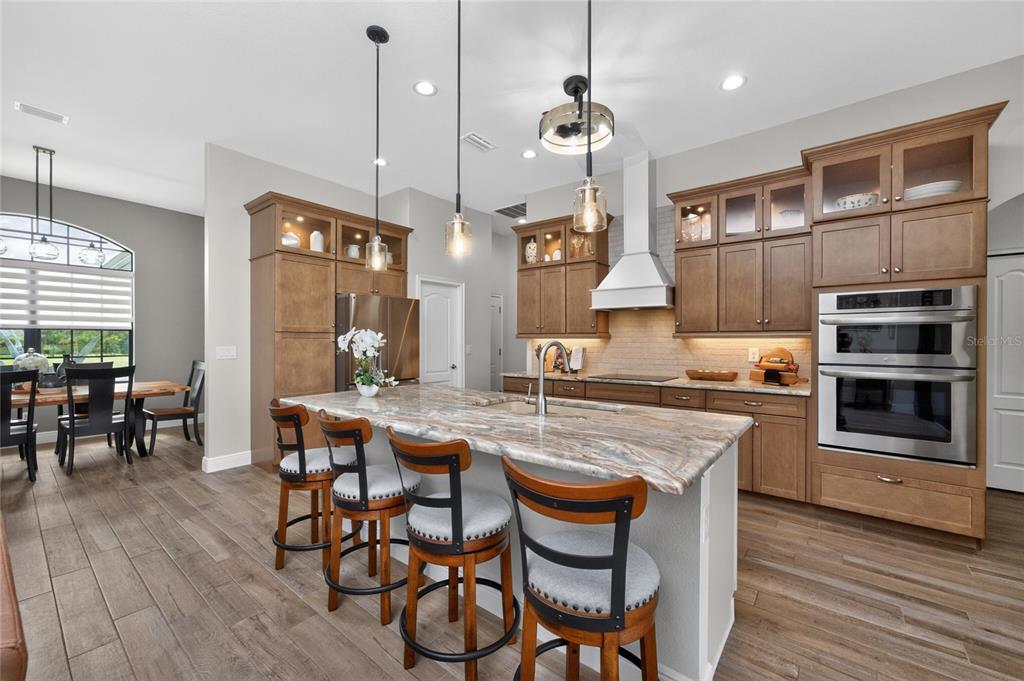 A kitchen with wood cabinets, a stone island, stainless steel appliances, and a dining area — 940 BOUNDARY BOULEVARD, ROTONDA WEST, FL