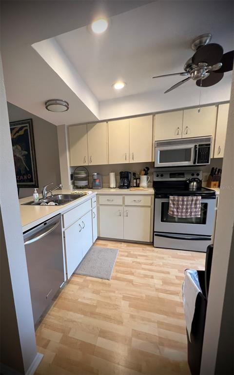 A kitchen features light-colored cabinets, stainless steel appliances, and light wood-look flooring — 4570 WEYBRIDGE UNIT 32, SARASOTA, FL