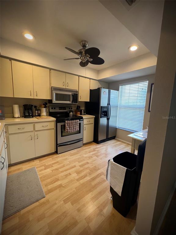 A kitchen features light-colored cabinets, stainless steel appliances, wood-look flooring, and a ceiling fan — 4570 WEYBRIDGE UNIT 32, SARASOTA, FL