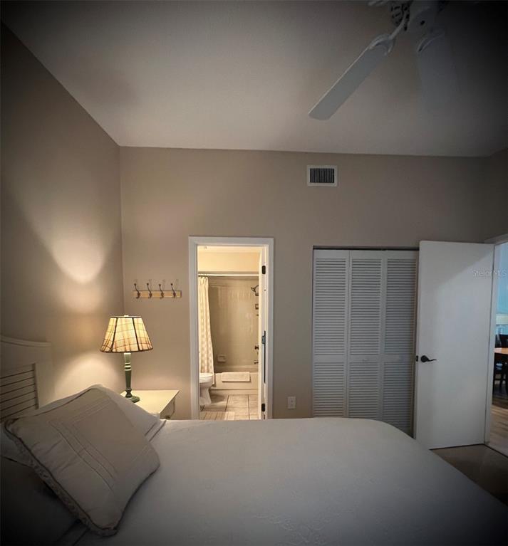 A bedroom features a bed, a bedside lamp, a bathroom doorway, and a closet — 4570 WEYBRIDGE UNIT 32, SARASOTA, FL