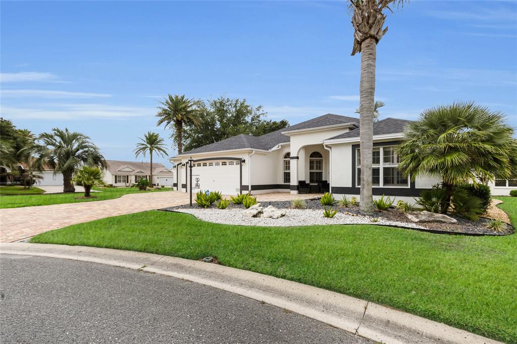 A single-story house with a white exterior, a paved driveway, and palm trees in the yard — 1718 MEANS LANE, THE VILLAGES, FL