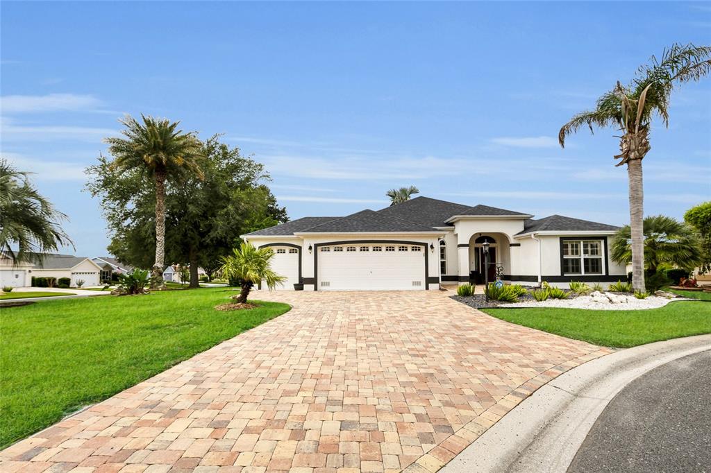 A single-story house with a white stucco exterior, dark trim, and a paved driveway — 1718 MEANS LANE, THE VILLAGES, FL
