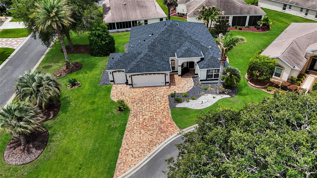 An aerial view shows a house with a dark shingled roof and a paved driveway — 1718 MEANS LANE, THE VILLAGES, FL