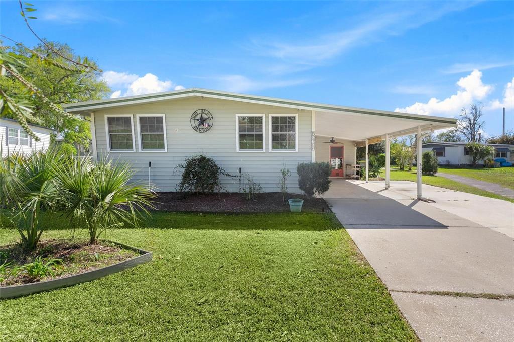 A single-story house with light siding, a front lawn, and an attached carport — 2621 CARPENTER PLACE, LEESBURG, FL