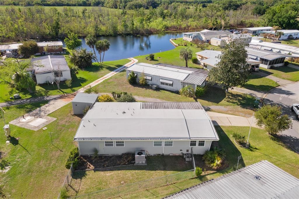 An aerial view shows several mobile homes situated near a small pond and green lawn — 2621 CARPENTER PLACE, LEESBURG, FL