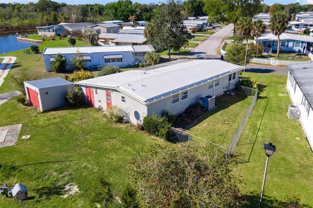 An aerial view shows a single-story house with a white roof and a detached shed — 2621 CARPENTER PLACE, LEESBURG, FL