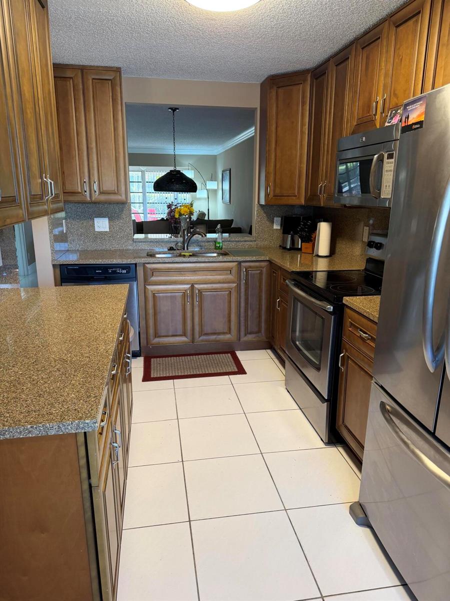 A kitchen with wood cabinets, granite countertops, stainless steel appliances, and white tile flooring — 8786 Belle Aire Drive, Boca Raton FL 33433, BOCA RATON, FL