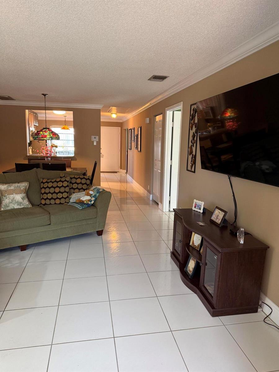 A living room features a green sofa, a dark wood media console, and tile flooring — 8786 Belle Aire Drive, Boca Raton FL 33433, BOCA RATON, FL