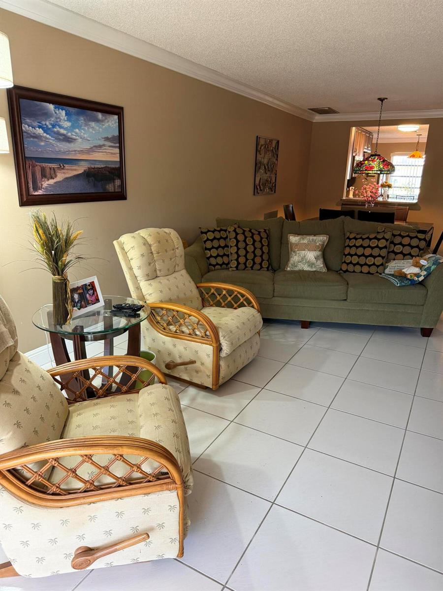 A living room features two rattan armchairs, a green sofa, and tile flooring — 8786 Belle Aire Drive, Boca Raton FL 33433, BOCA RATON, FL