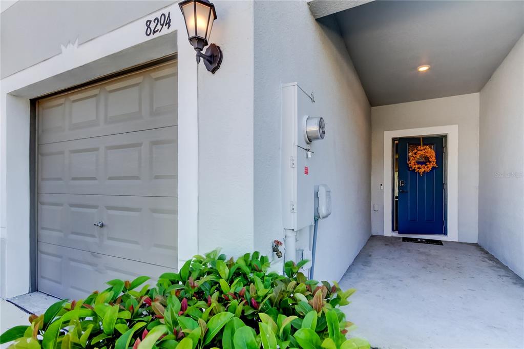 A gray garage door and a blue front door are visible on this home exterior — 8294 CORNER PINE WAY, NEW PORT RICHEY, FL