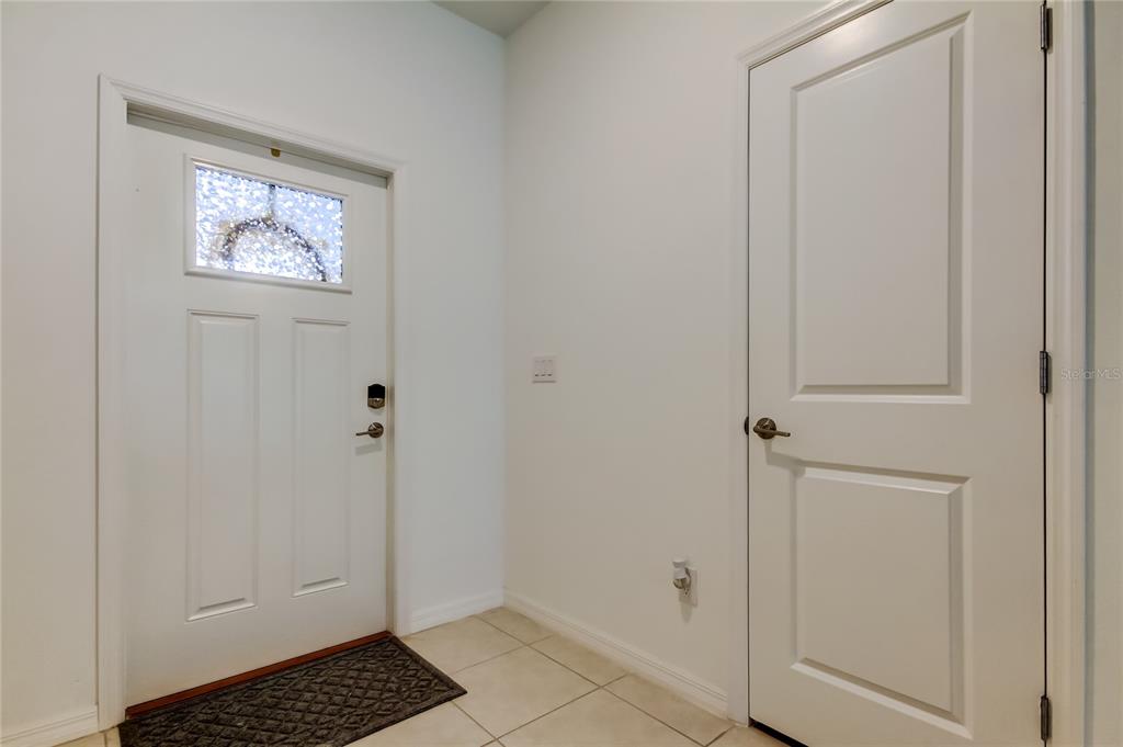 An entryway features a white front door with a glass insert, tile flooring, and a closet — 8294 CORNER PINE WAY, NEW PORT RICHEY, FL