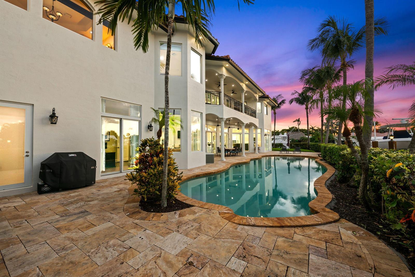 A two-story house with a pool, stone patio, and palm trees at sunset — 1261 NE 27th Way, Pompano Beach FL 33062, POMPANO BEACH, FL
