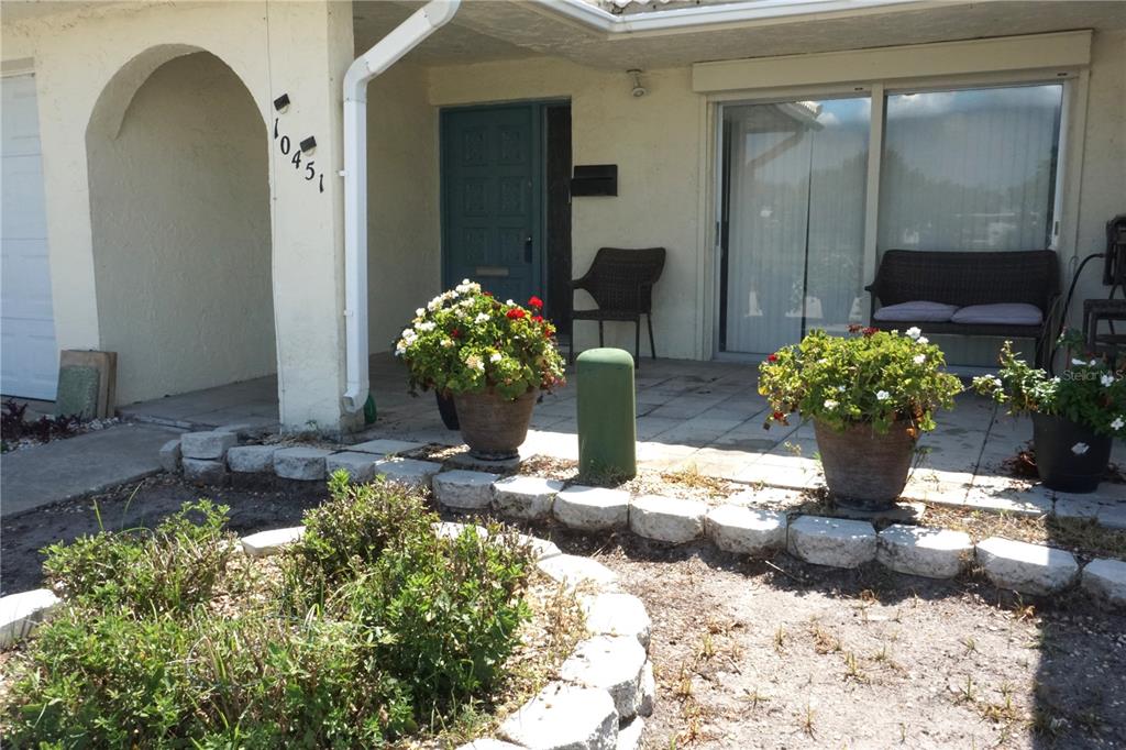 The exterior of a home features a covered patio, potted plants, and a front door — 10451 AZALEA PARK DRIVE N UNIT 2, PINELLAS PARK, FL