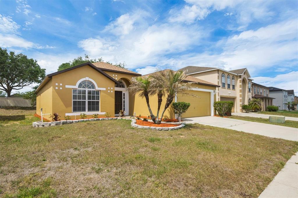 A single-story yellow stucco house with a two-car garage and a front palm tree — 140 MILESTONE DRIVE, HAINES CITY, FL