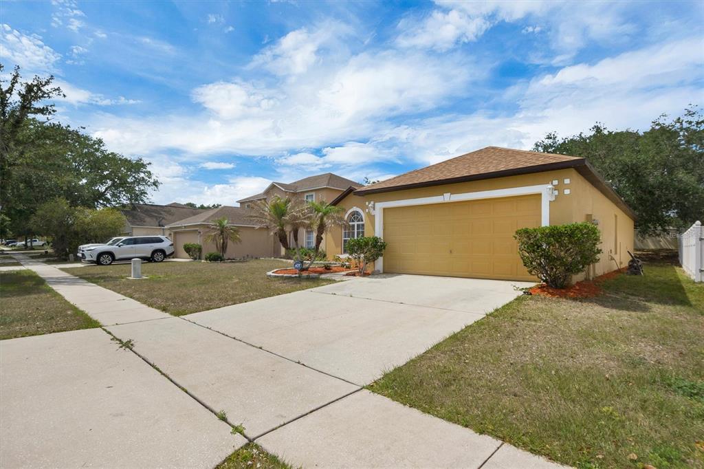 A single-story house with a tan stucco exterior, a two-car garage, and a concrete driveway — 140 MILESTONE DRIVE, HAINES CITY, FL