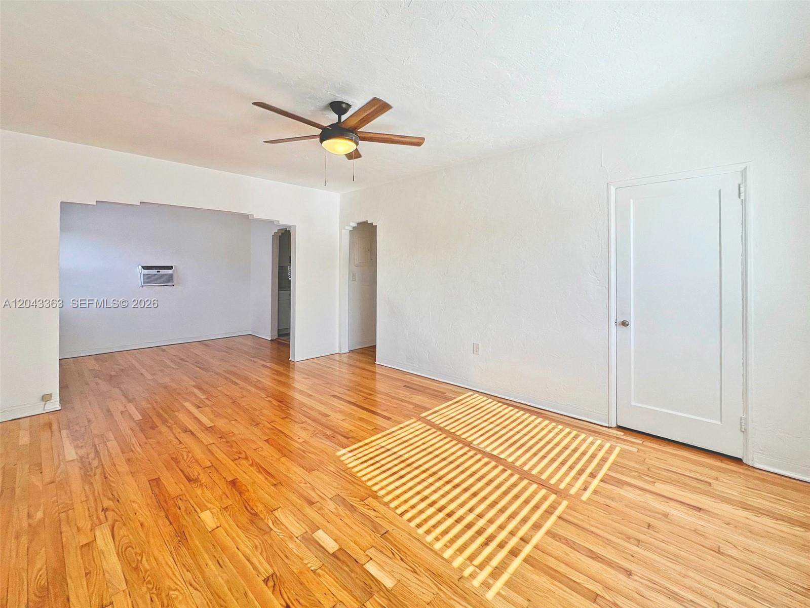 An empty room features hardwood floors, a ceiling fan, and an arched entryway — 2102 SW 14 Ter # 1466, Miami FL 33145, MIAMI, FL