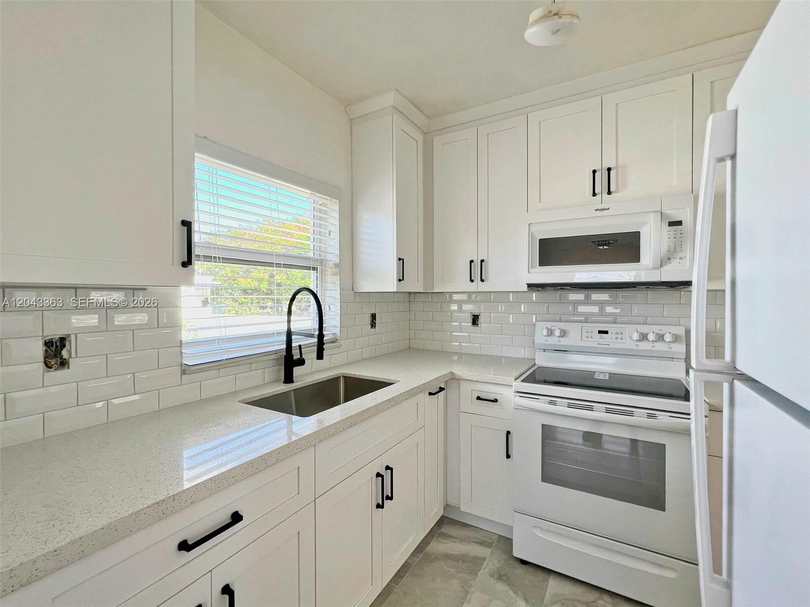 A kitchen features white cabinets, a subway tile backsplash, quartz countertops, and stainless steel appliances — 2102 SW 14 Ter # 1466, Miami FL 33145, MIAMI, FL