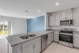 A kitchen features gray cabinets, granite countertops, stainless steel appliances, and a blue accent wall — 2723 SILVER CANOE DRIVE, EDGEWATER, FL