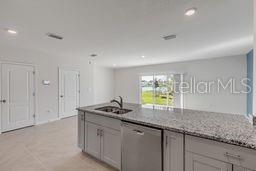 A kitchen features light gray cabinets, granite countertops, stainless steel appliances, and tile flooring — 2723 SILVER CANOE DRIVE, EDGEWATER, FL