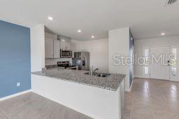 A kitchen with granite countertops, stainless steel appliances, and light cabinetry opens to a foyer — 2723 SILVER CANOE DRIVE, EDGEWATER, FL