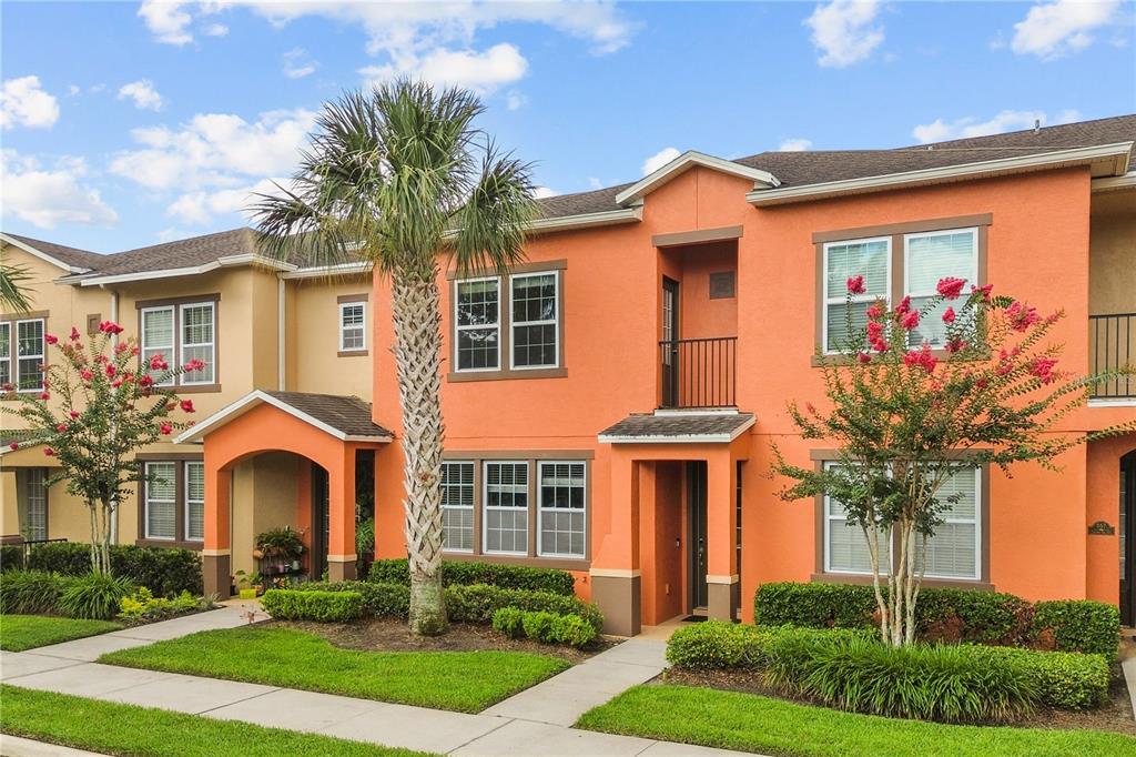 A two-story orange stucco townhouse with a palm tree and blooming crape myrtle trees — 561 TELFAIR SQUARE COURT, SANFORD, FL