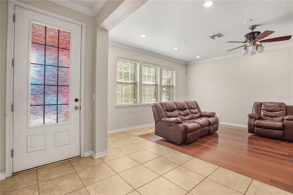 A living room with tile flooring, wood floors, a ceiling fan, and a front door — 561 TELFAIR SQUARE COURT, SANFORD, FL