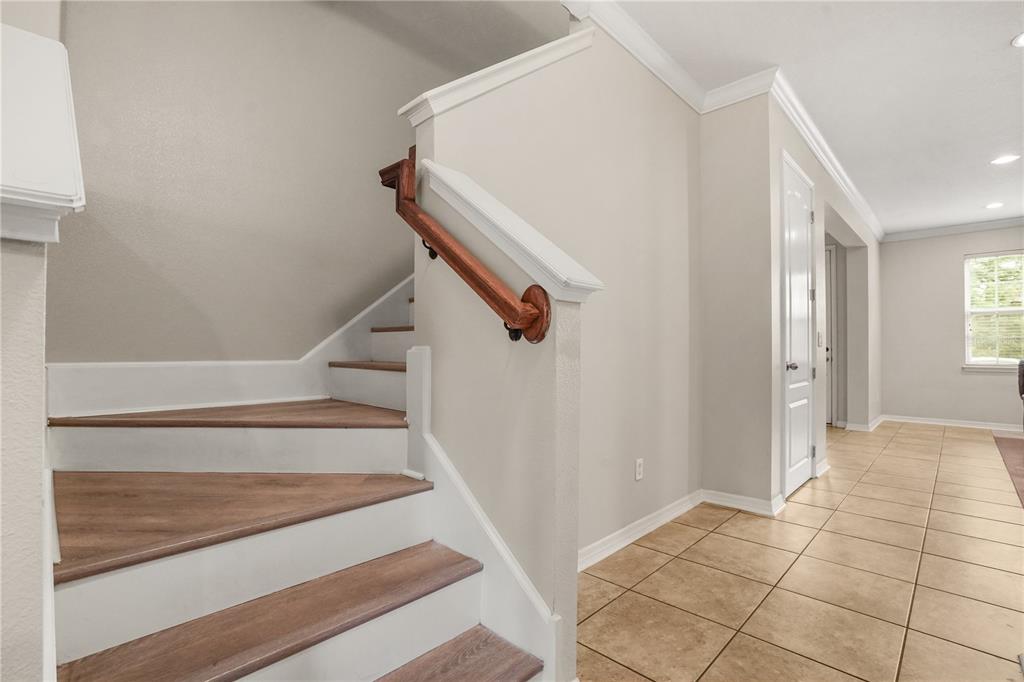 A staircase with wood-look treads and a white handrail sits beside a tiled hallway — 561 TELFAIR SQUARE COURT, SANFORD, FL