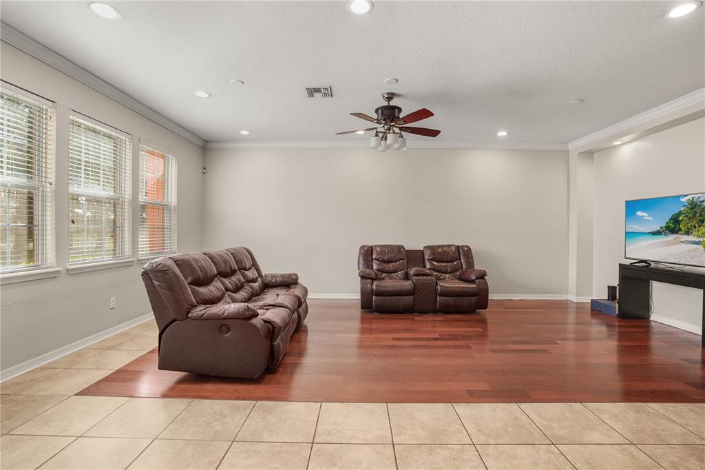 A living room features a wood floor inlay, tile flooring, leather recliners, and a television — 561 TELFAIR SQUARE COURT, SANFORD, FL
