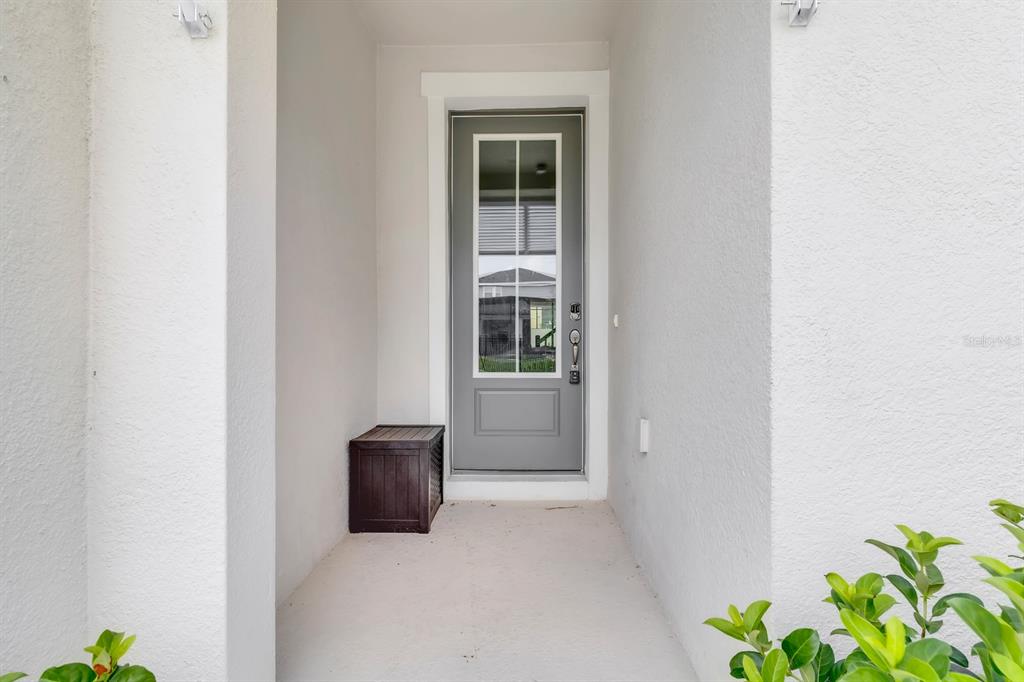 A gray front door with a glass window panel is set within a white entryway — 2312 ZABALLINA PLACE, KISSIMMEE, FL